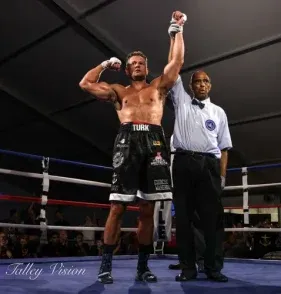 Boxer with his arm raised by the referee after a fight